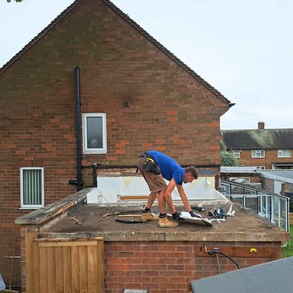 Worker on flat roof mid-strip before EPDM