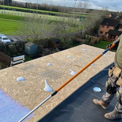 Roofer on flat roof OSB decking sports field view