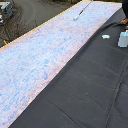 EPDM membrane being laid with adhesive roller