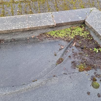 Damaged flat roof corner with concrete coping