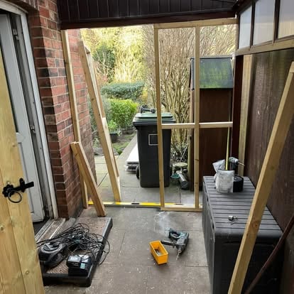 Dark brown lean-to under construction against brick wall