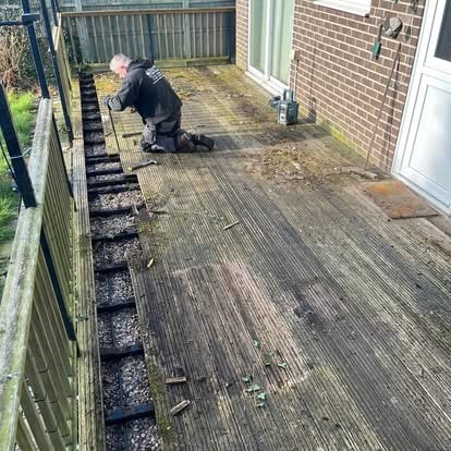 Worker removing old rotted decking with metal pergola frame