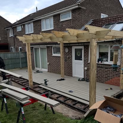 Composite decking boards being laid timber pergola frame