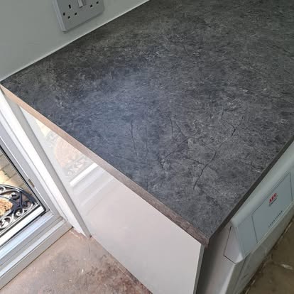 Dark stone worktop fitted on white utility room cabinet