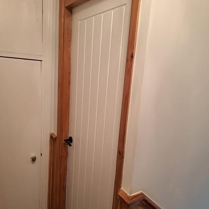 White panelled door with pine surround near staircase