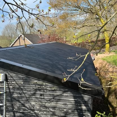 Black corrugated metal roof on dark timber barn