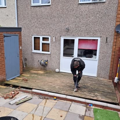 Worker removing old decking with crowbar on terrace house