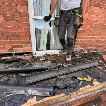 Worker stripping old felt from Victorian bay window roof