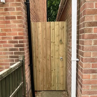 New vertical board timber side gate between brick walls