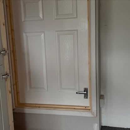 White six-panel door with pine lining being fitted