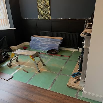 Dark panelled room with floor underlay being prepared
