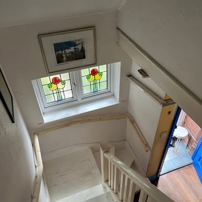 White painted staircase with stained glass landing window
