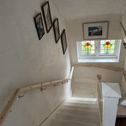 White staircase with pine handrail and stained glass