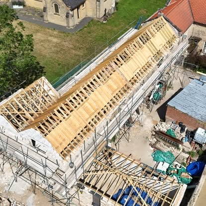 Aerial view of stone barn with new long roof structure