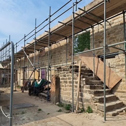Historic stone building with scaffolding and stone steps