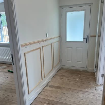 White wall panelling being fitted in hallway