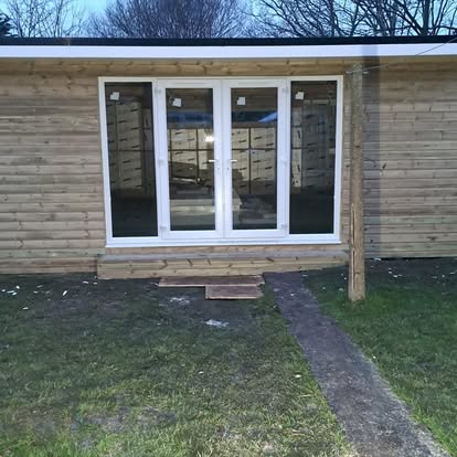 Large timber building with UPVC windows in field