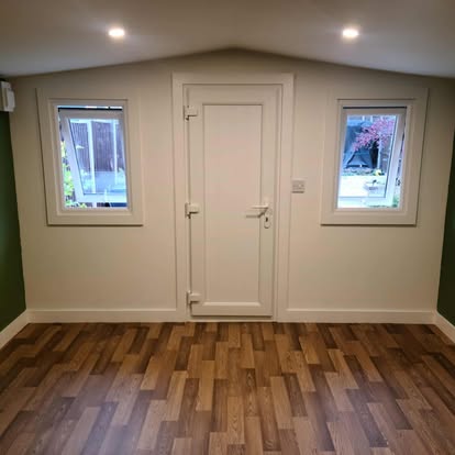 Completed garden room interior with green walls and wood floor