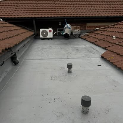 New grey flat roof between two pitched tile roofs