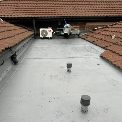 Completed grey flat roof between pitched tile roofs